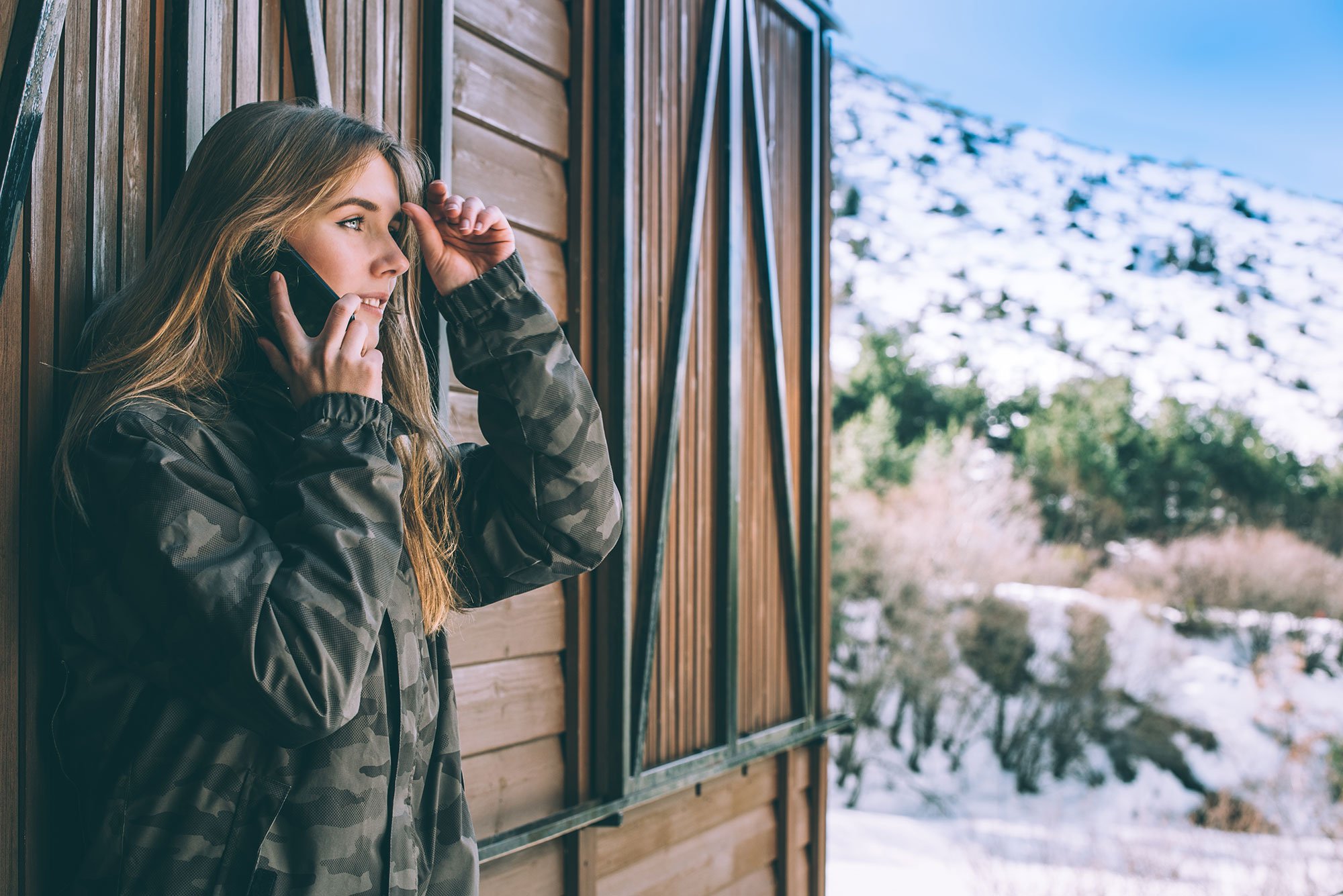 woman-mobile-phone-rural-cabin-mountain-winter-snow
